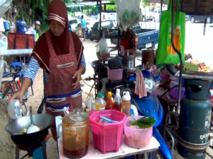 Street vendor cooking on a scooter stove